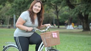 exercícios aeróbicos para emagrecer - mulher asiática um pouco gordinha andando de bicicleta